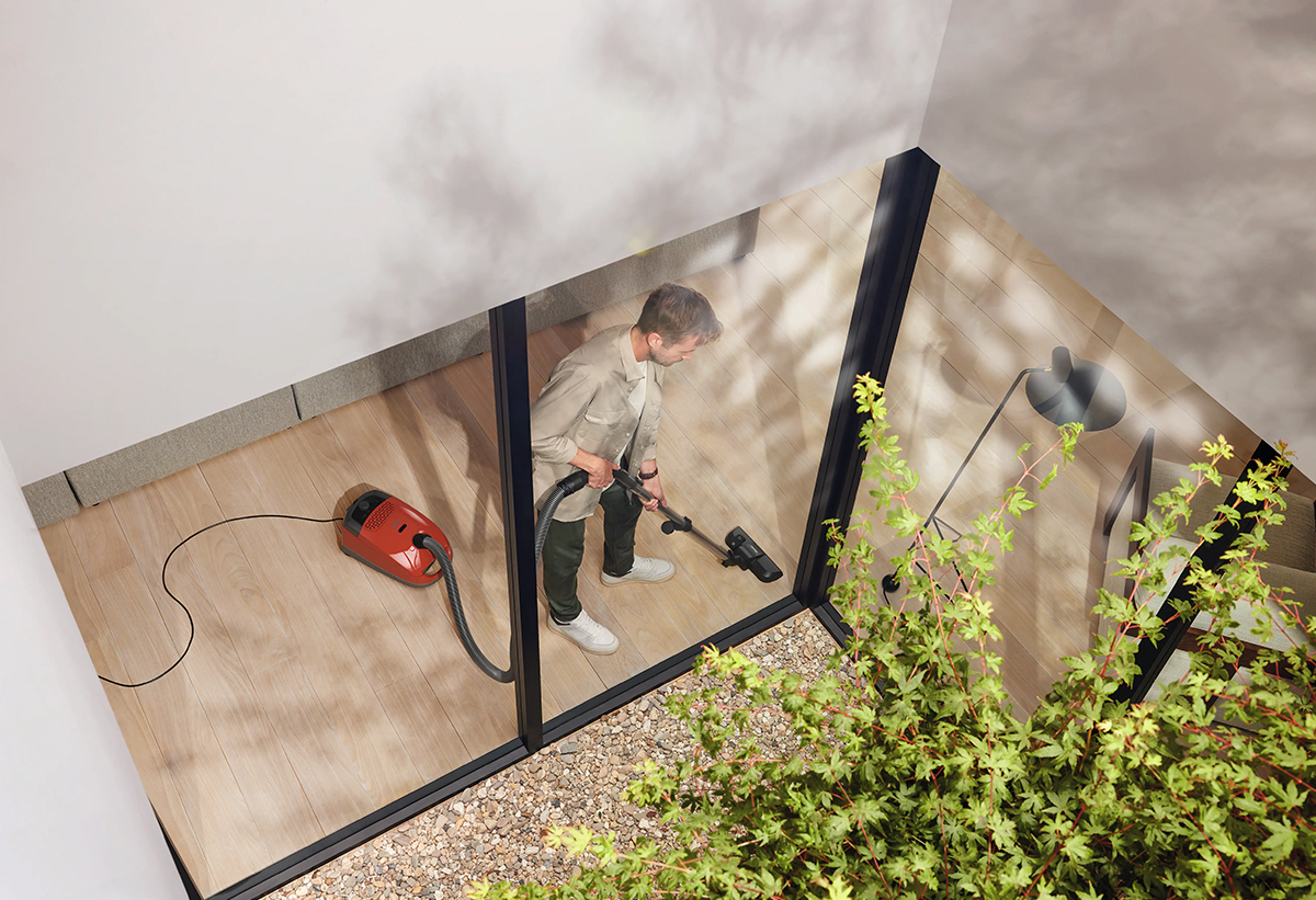 Ένας άντρας καθαρίζει το πάτωμα του σπιτιού του με τη σκούπα.